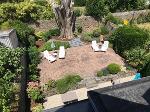 A patio with four white lounge chairs and a small table, surrounded by a stone wall and various plants. - Villa HomeMalo 250m from the beach and the Sillon in Saint-Malo (Saint-Malo)