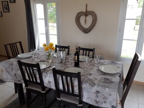 A dining table set with plates, glasses, and a bottle, surrounded by chairs.