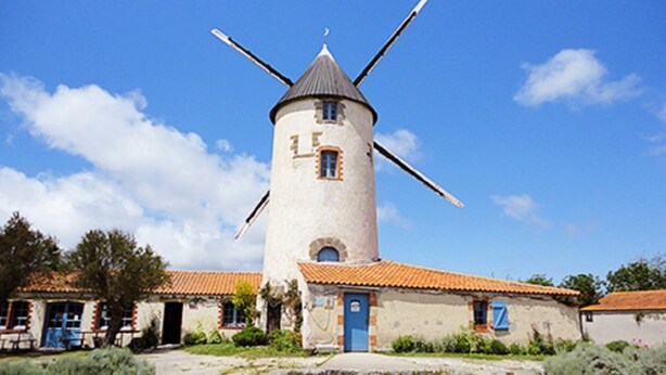 A windmill with a traditional design, a small attached building with a blue door, and a clear blue sky. - Long House Retreat, Sleeps 6,St Jean de Mont.
 (Saint-Jean-De-Monts)
