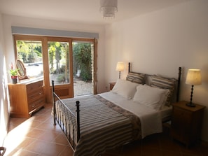 Quarto com uma cama, duas mesas de cabeceira com abajures, um penteado e um espelho.