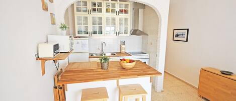 A compact kitchen with a central island, white cabinetry, and a tiled backsplash.