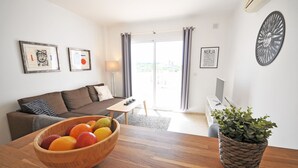 Una sala de estar moderna con una mesa de centro de madera, un sofá marrón y una mesa de comedor con un frutero.