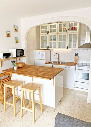 A compact kitchen with a wooden island, white cabinetry, and a built-in oven. - Rabat 14 (Nerja)