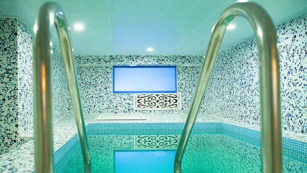 Una piscina con paredes de mosaicos y un panel decorativo central.