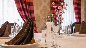 Una mesa de comedor dispuesta con platos, cubiertos y un florero con flores.