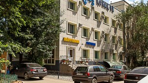 Un edificio con varias ventanas, un letrero que dice "TOPOA3 KOHANUI" y coches estacionados adelante.