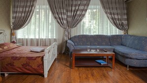 Una habitación con una cama, un sofá, una mesita de café y una ventana con cortinas.