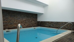 Una piscina rectangular interior con un muelle de madera alrededor.