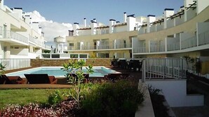 Un hotel moderno con piscina, zona de estar exterior y un jardín bien cuidado.
