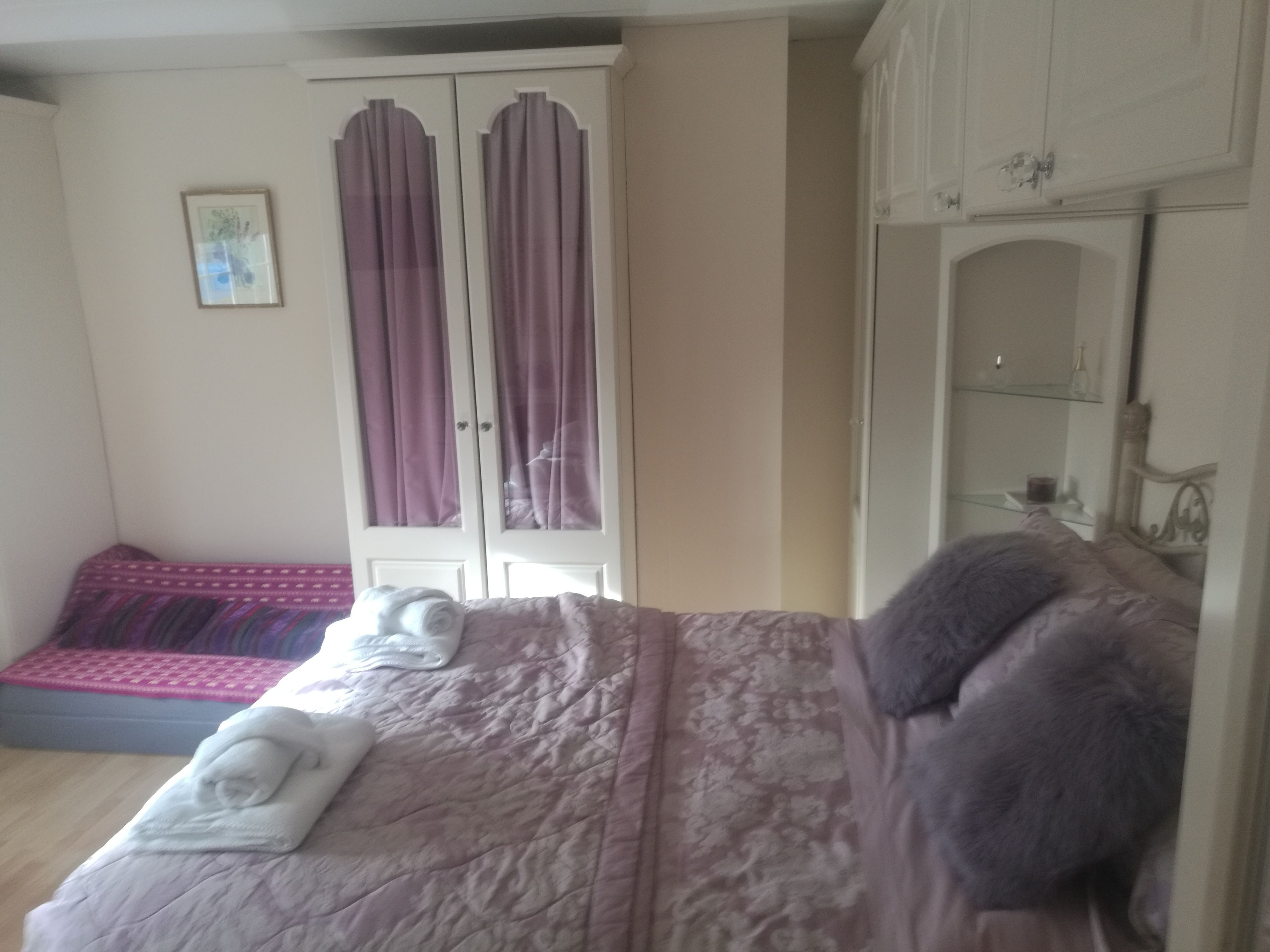 A bedroom with a bed, a wardrobe, and a small seating area.