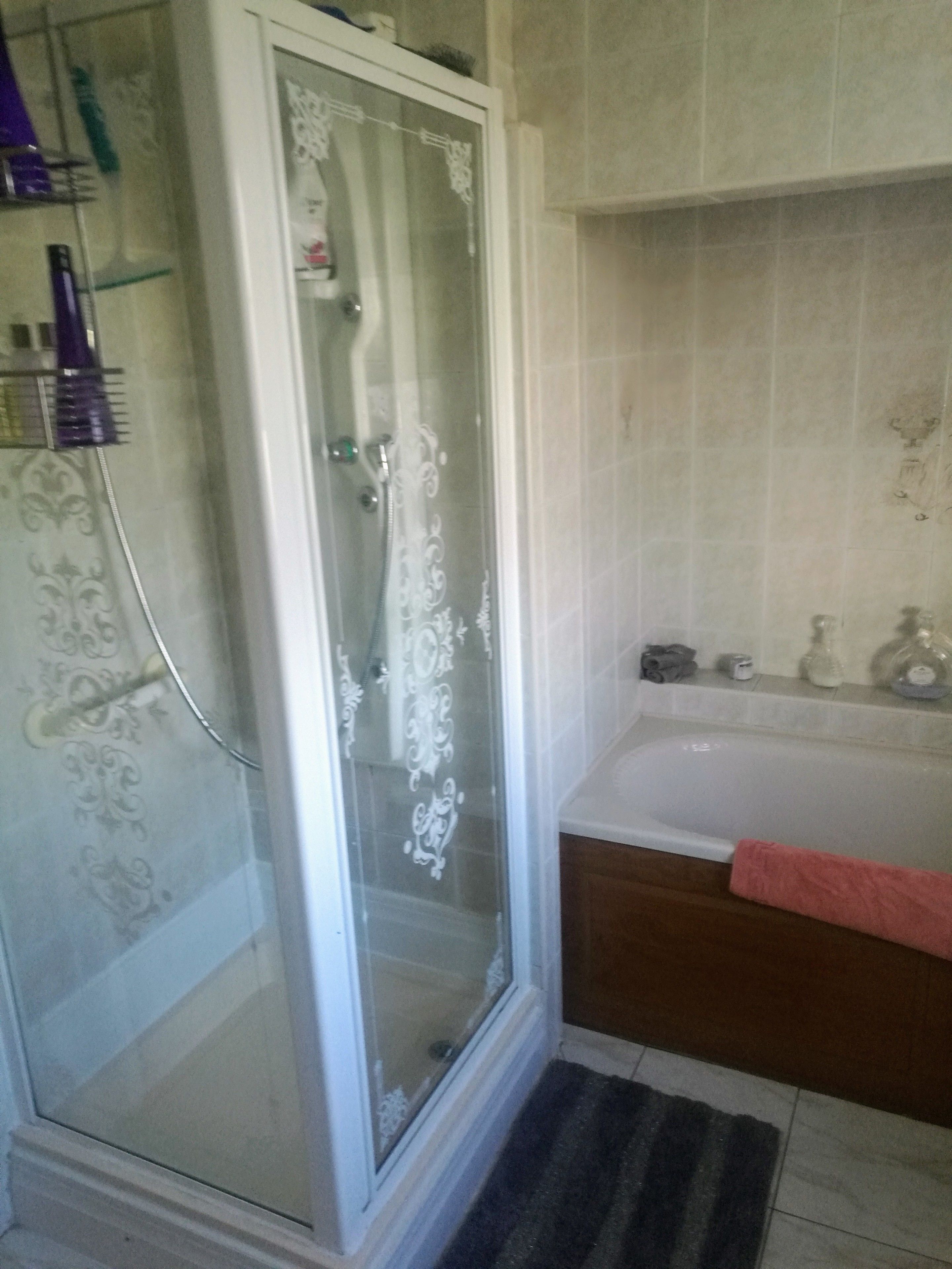 A bathroom with a glass-enclosed shower, a bathtub, and a vanity with toiletries.