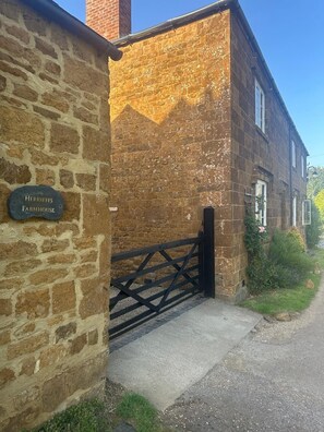 Ein Steinhaushof mit schwarzem Tor, einer Ziegelmauer und einem Schild mit der Aufschrift 'Herrieffs Farmhouse'.