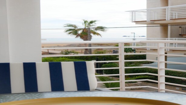 A balcony with a view of the beach, palm trees, and a white railing. - Apartment at 20 m.de the beach with private parking bicycles (Peñíscola)