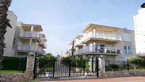 A multi-story residential building with balconies, a gated entrance, and a clear sky. - Apartment at 20 m.de the beach with private parking bicycles (Peñíscola)