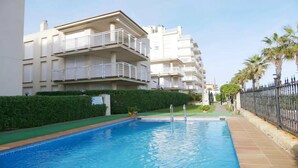 A swimming pool with a clear blue water surface, surrounded by a low hedge and a metal fence. - Apartment at 20 m.de the beach with private parking bicycles (Peñíscola)