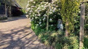 Un sentier pavé de pierres menant à un bâtiment rustique en bois, surmonté d’un toit de chaume.
