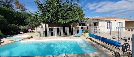 A swimming pool with a deck, surrounded by a fence and trees.