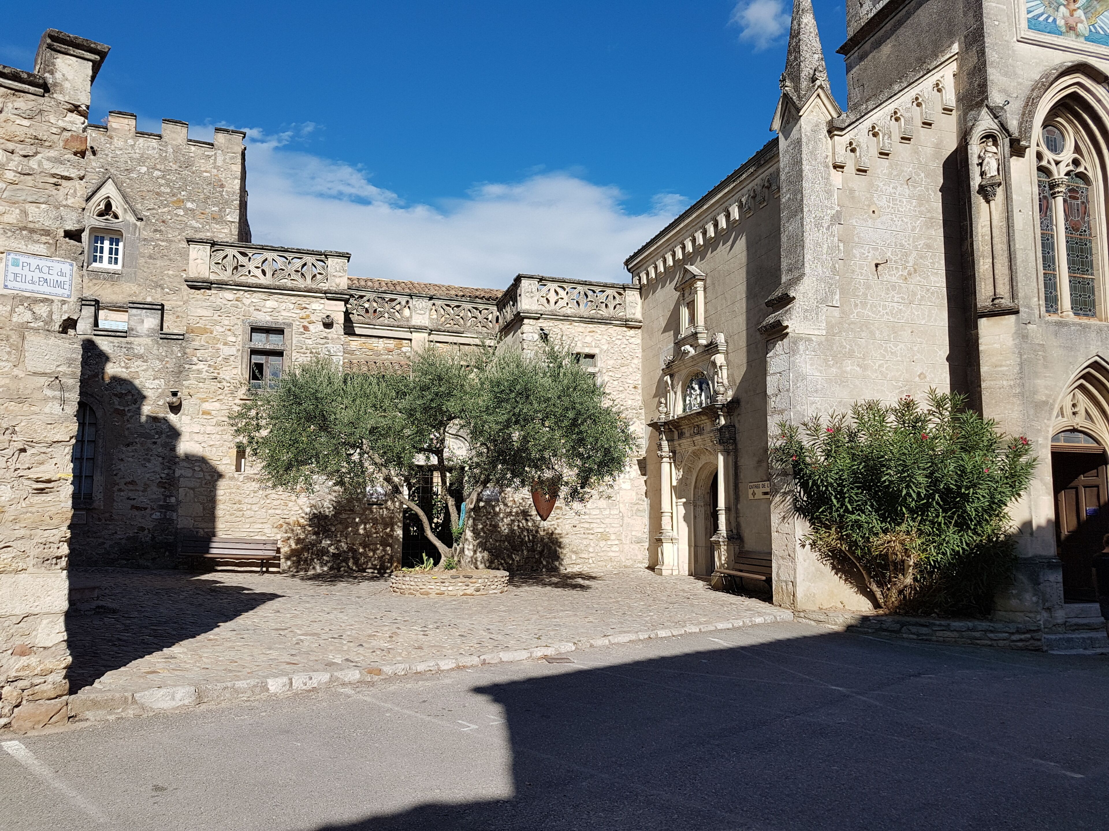 Un bâtiment historique en pierre, doté d’une cour intérieure, comprenant une porte, une statue et un panneau indiquant un lieu d’intérêt.