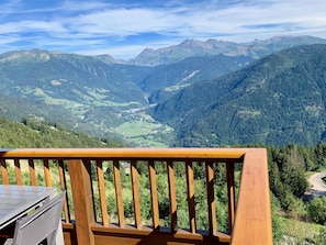Una terraza de madera con vistas a un valle y montañas.