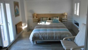 Een slaapkamer met een bed, nachtkastjes, een stoel en een raam.