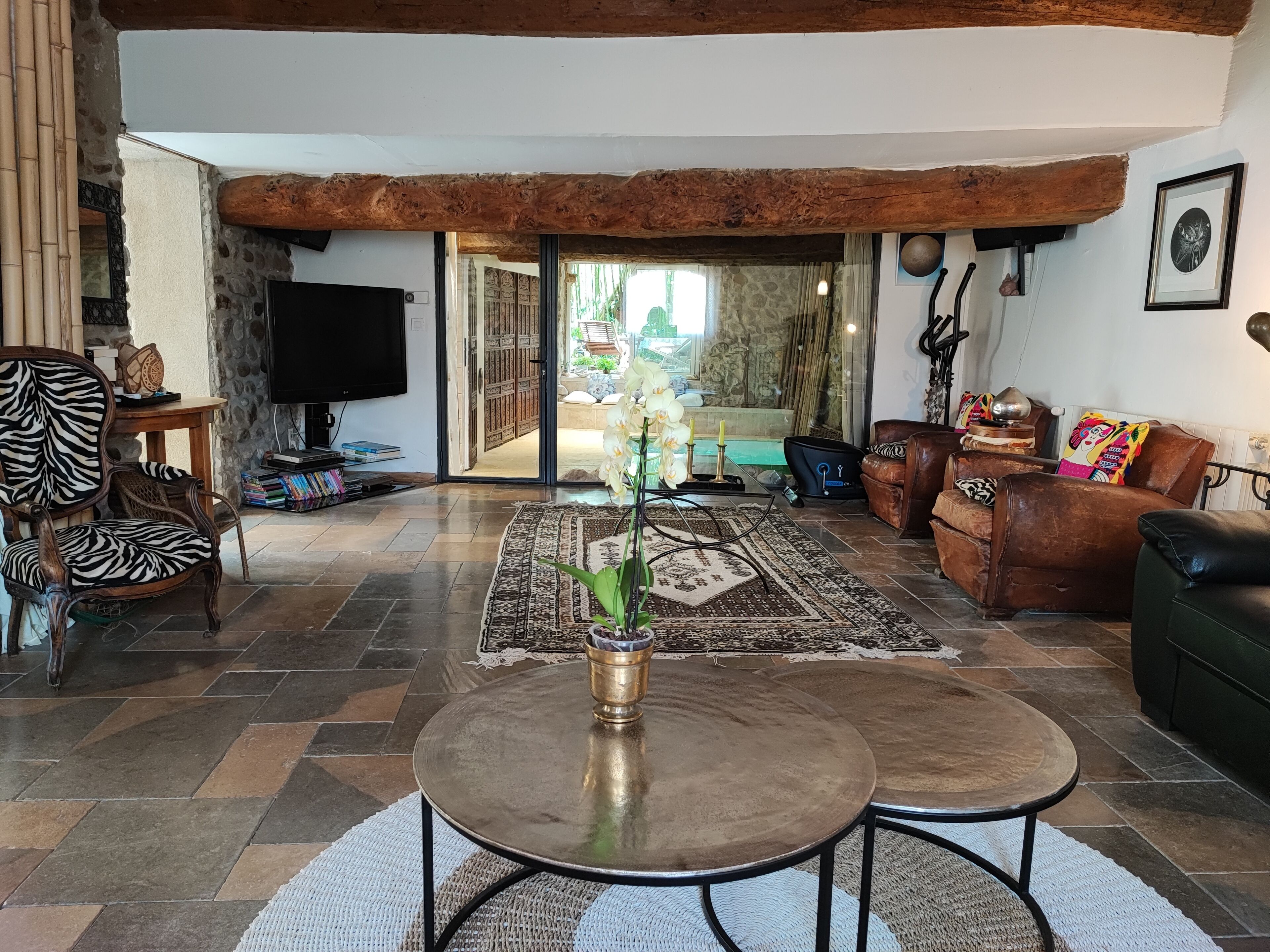 A spacious living room with a large TV, a zebra-patterned chair, a brown leather sofa, and a coffee table.