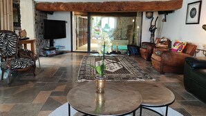 A spacious living room with a large TV, a zebra-patterned chair, a brown leather sofa, and a coffee table. - Mansion - Massillargues Attuech (Massillargues-Attuech)
