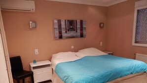 A bedroom with a bed, a nightstand, a chair, a painting on the wall, and a window with blinds. - Fantastic Villa Amare on top of the Montemar (Benissa)