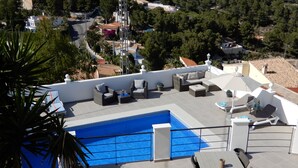 A rooftop pool area with lounge chairs and a table, surrounded by a white wall and a view of the neighborhood. - Fantastic Villa Amare on top of the Montemar (Benissa)