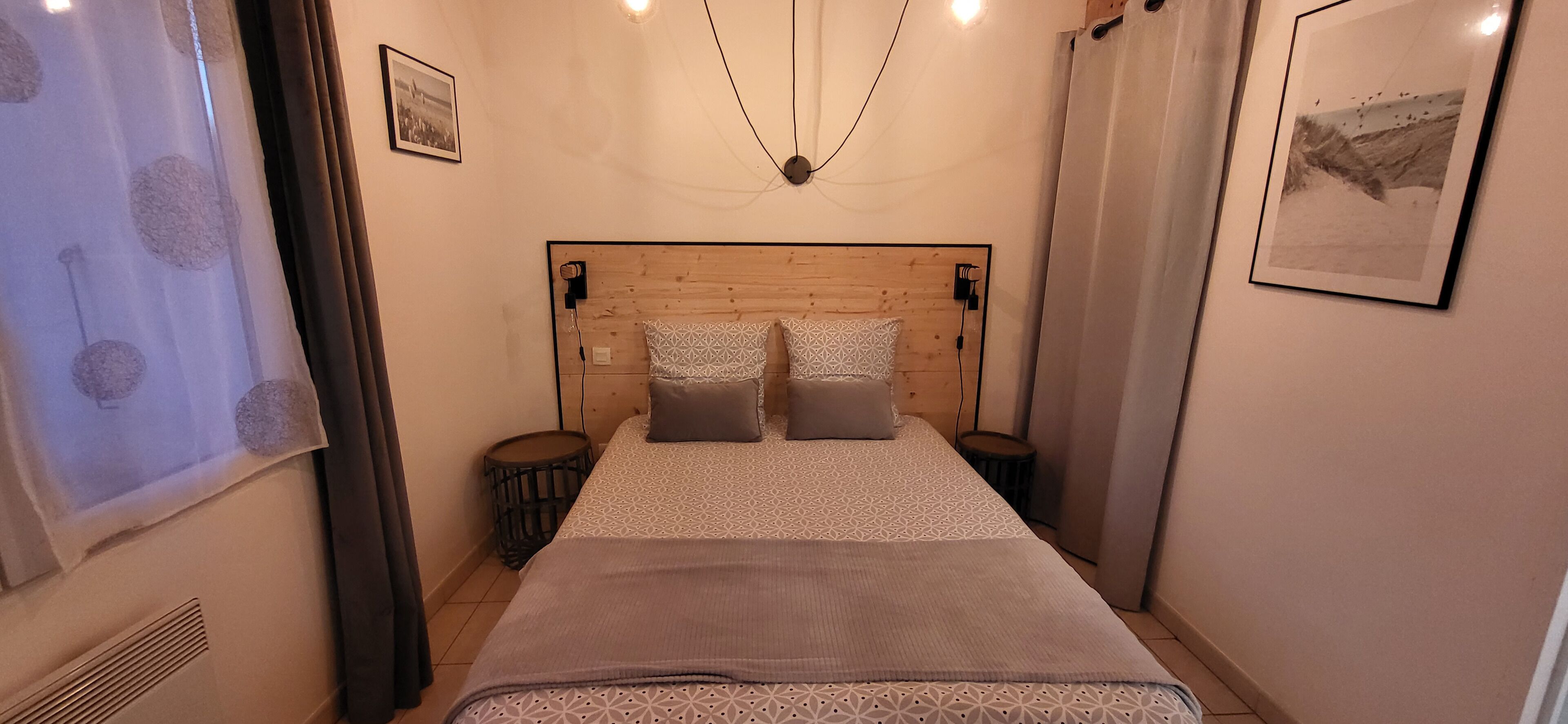 A bedroom with a wooden headboard, two bedside tables, a patterned bedspread, and a framed picture on the wall.