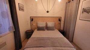 A bedroom with a wooden headboard, two bedside tables, a patterned bedspread, and a framed picture on the wall. - studio - ST PIERRE D OLERON (Saint-Pierre-D'oléron)