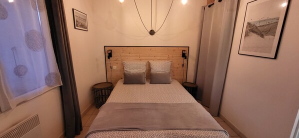 A bedroom with a wooden headboard, two bedside tables, a patterned bedspread, and a framed picture on the wall.