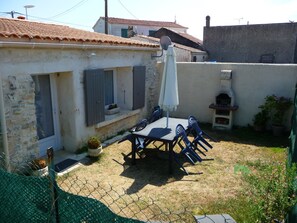 A patio with a table and chairs, a small garden, and a stone wall. - studio - ST PIERRE D OLERON (Saint-Pierre-D'oléron)