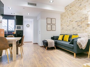 Un salon moderne avec un canapé gris, un plancher en bois et un mur en briques.