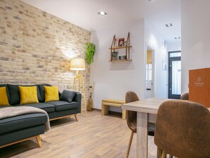 Un salon moderne avec un mur en briques, un canapé agrémenté de coussins jaunes, une table basse en bois et une lampe.