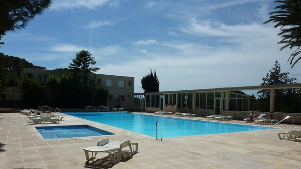 Una piscina con lettini e un edificio sullo sfondo.