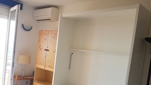 Una camera da letto con un letto, un armadio, una scrivania e una lampada.