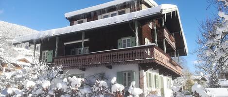 Um edifício de vários andares com telhado coberto de neve e varandas.