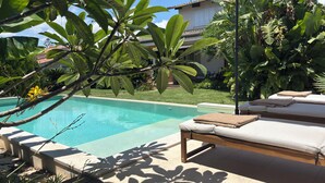 Ein Poolbereich mit Liege, Tisch und Sonnenschirm.