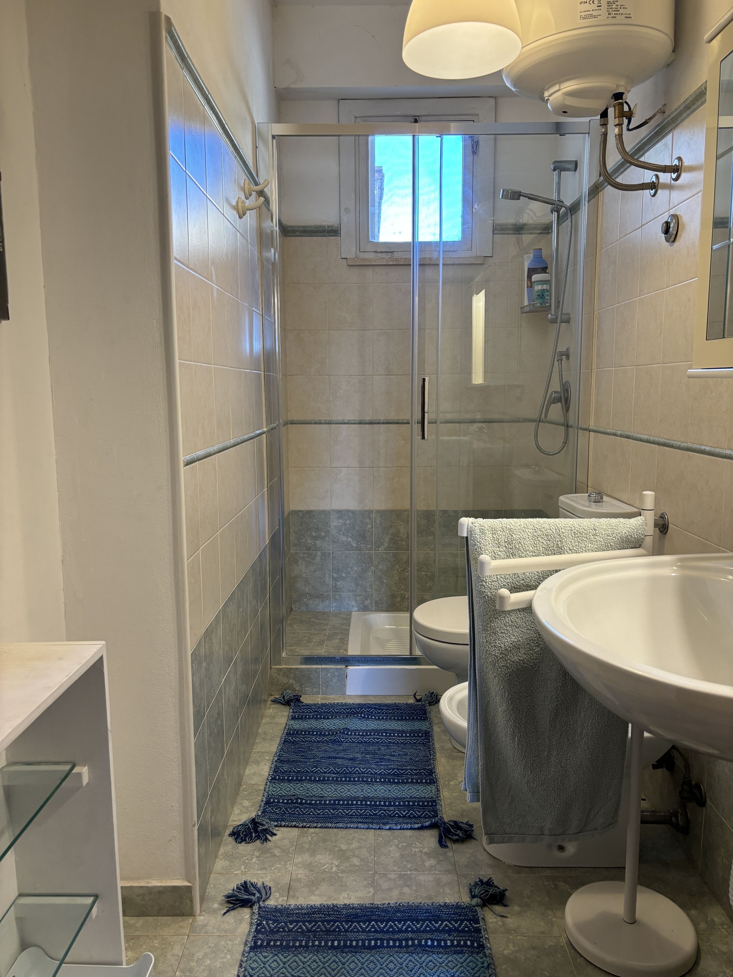 A modern bathroom with a glass-enclosed shower, a white sink, and a toilet.