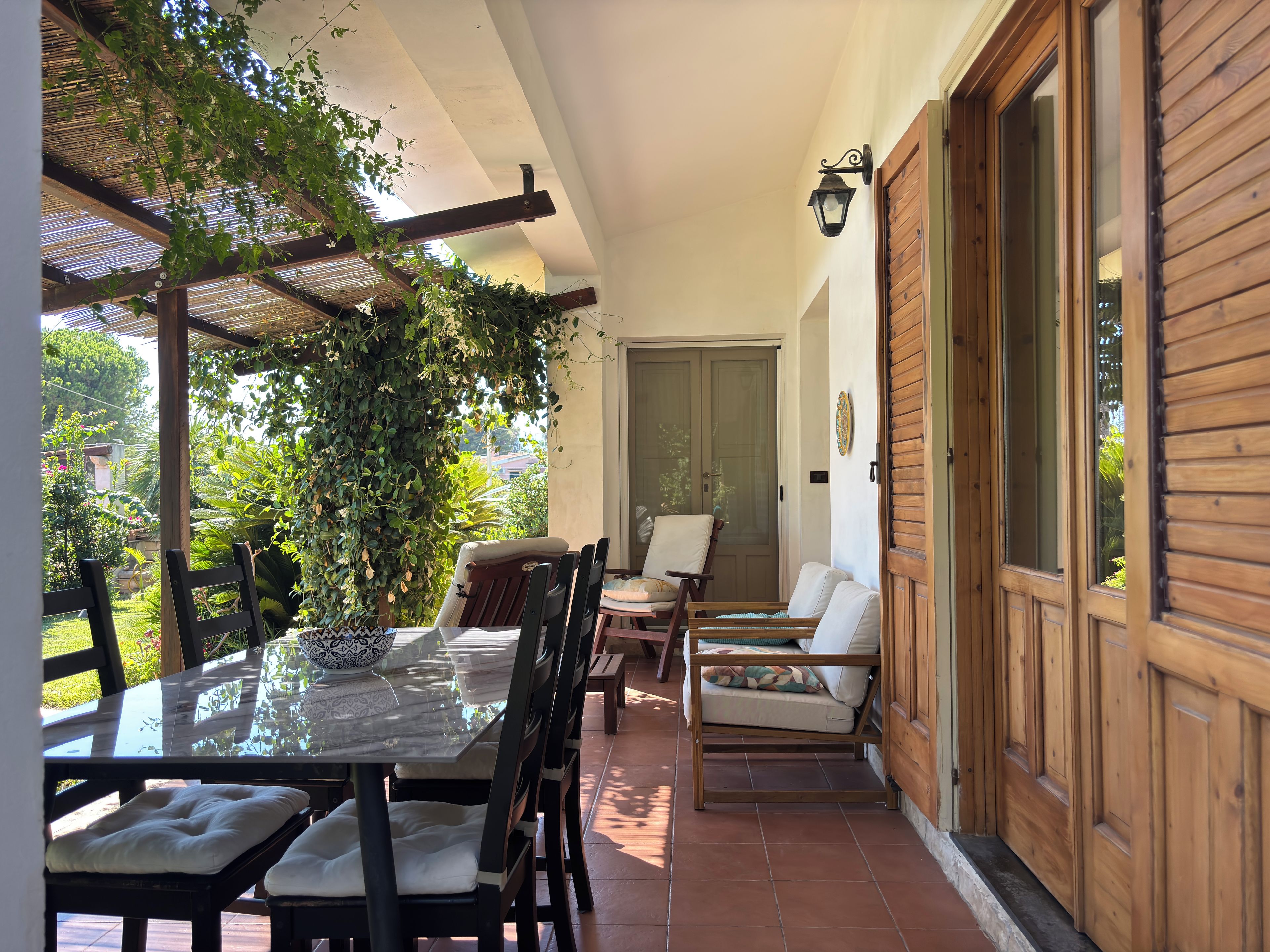 An outdoor patio with a glass table, chairs, and a wooden door.
