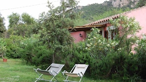 A garden with two lounge chairs and a building with a red roof.