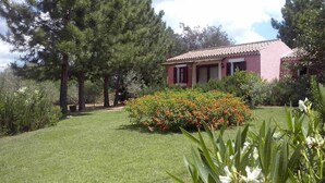 A house with a red roof and a well-maintained garden with various plants and flowers.