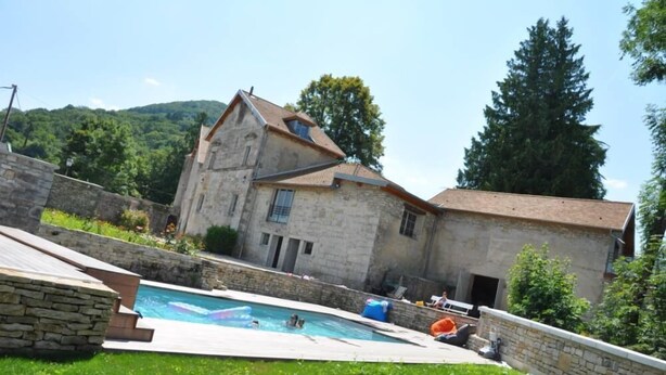 A stone building with a swimming pool in the foreground.