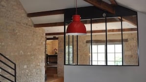 A dining area with a long table, red cushions, and a red pendant light.