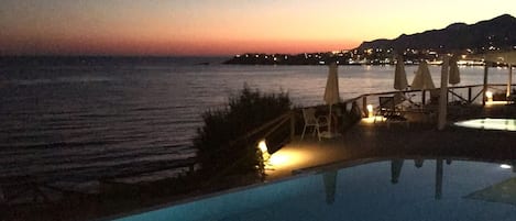 Una piscina infinita con vistas al océano al anochecer.