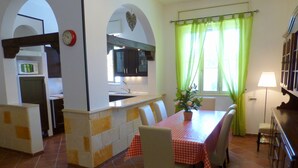 Un coin repas avec une nappe à carreaux rouges, des chaises et une plante en pot.