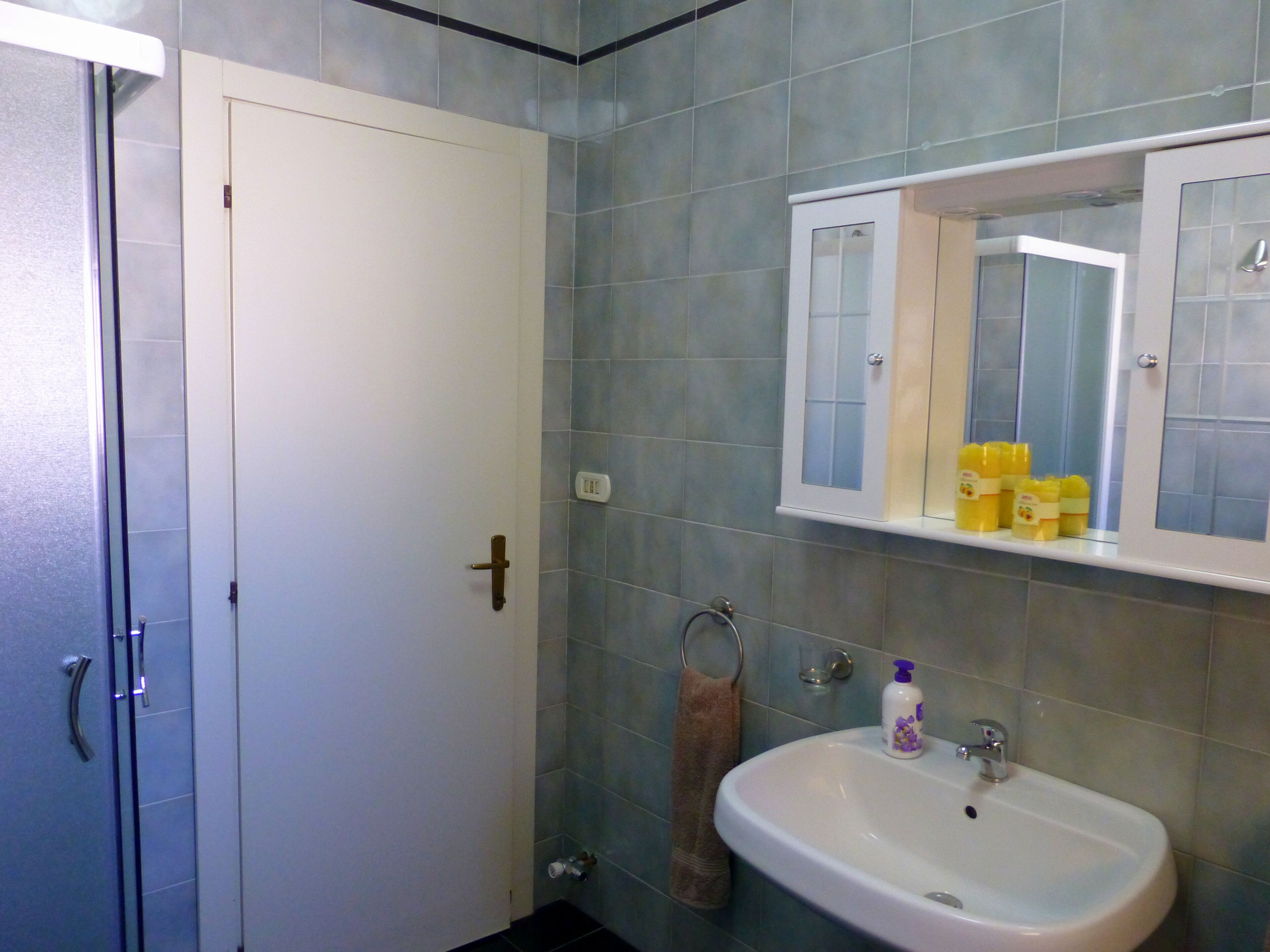 Un baño con un lavabo blanco, un espejo y una toalla colgada en un perchero.