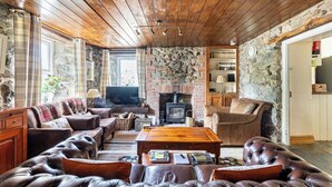Ein gemütliches Wohnzimmer mit Ledersofas, einem Holztisch und einem Kamin aus Stein.