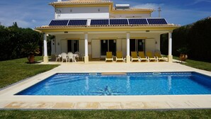 A house with a swimming pool, solar panels, and a covered patio with chairs. - Villa Borboleta, Albufeira.  Quality Villa, Private Pool, Air Conditioning, 3 Bedrooms, 4 Bathrooms. (Albufeira)