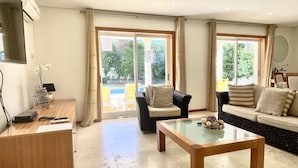 A spacious living room with a sofa, armchairs, a coffee table, and a TV. - Villa Borboleta, Albufeira.  Quality Villa, Private Pool, Air Conditioning, 3 Bedrooms, 4 Bathrooms. (Albufeira)